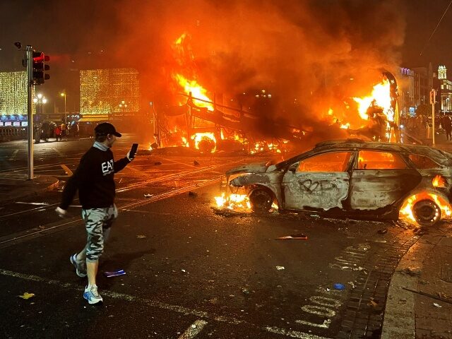 Flames rise from a car and a bus, set alight at the junction of Bachelors Walk and the O'Connell Bridge, in Dublin on November 23, 2023, as people took to the streets in protest following the stabbings earlier in the day. Protesters in Dublin on Thursday torched a car and …
